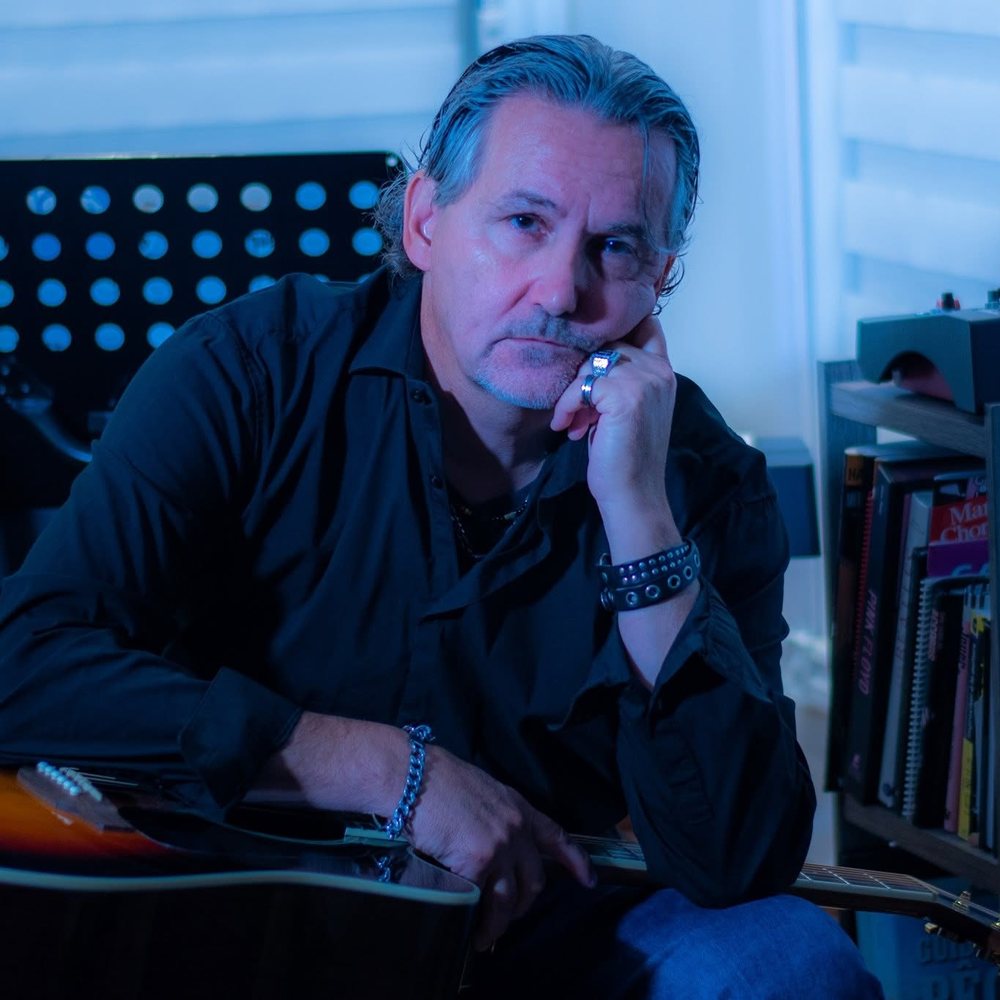 Pierre Dassylva dans son studio, guitare acoustique a la main